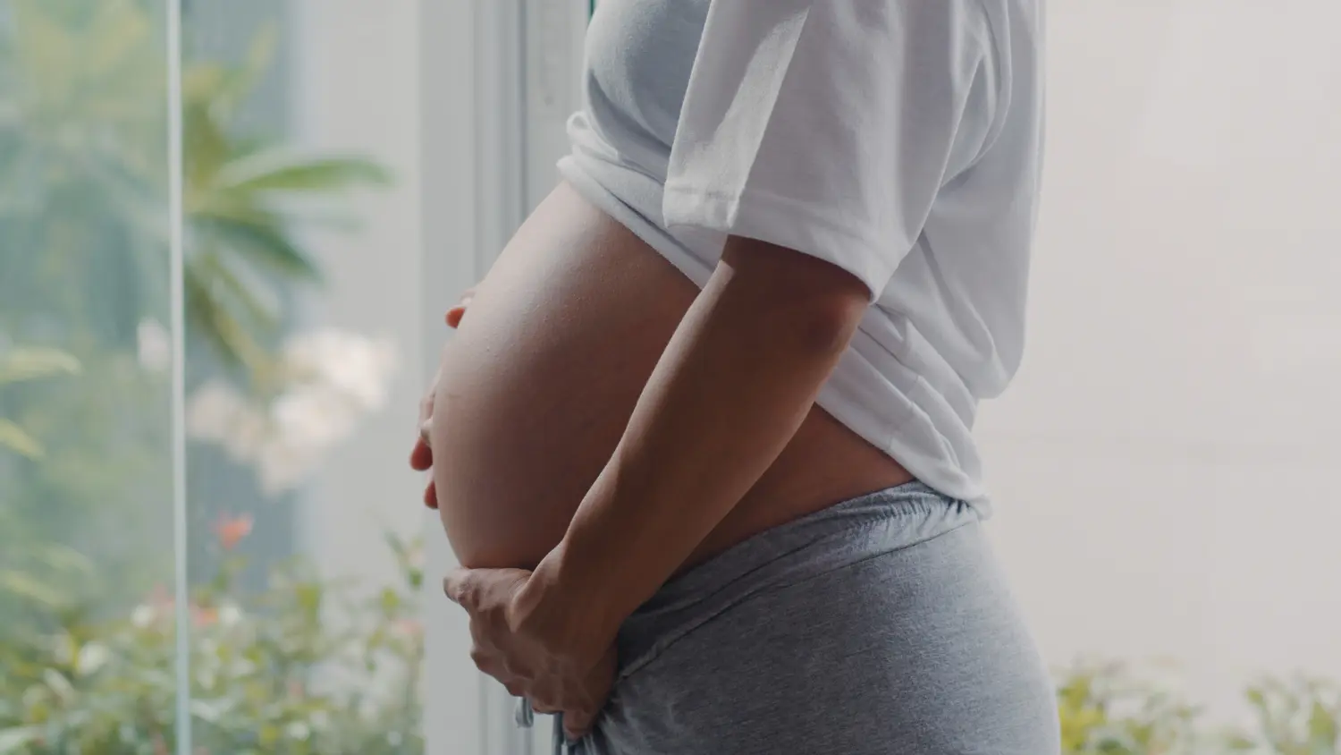 Mulher grávida de lado segurando a barriga sem dor nas pernas na gravidez.